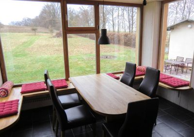 Essbereich mit Panoramablick im Bahnwärterhaus – großer Holztisch mit Lederstühlen und Fensterfront