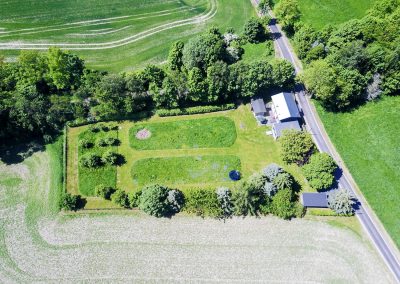 Luftaufnahme des Bahnwärterhauses mit großem Garten und umgebenden Feldern